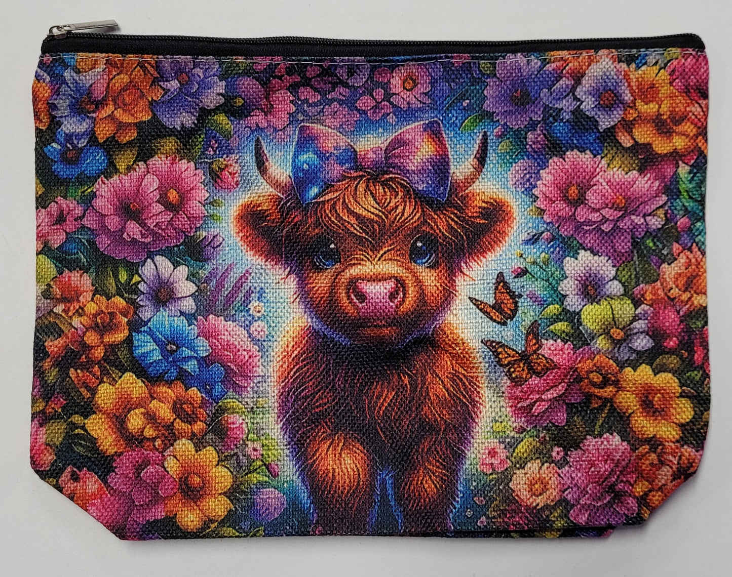 Pouch with a colorful design of a Highland cow with a bow surrounded by flowers and butterflies.